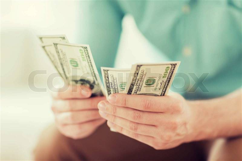 Savings, finances, economy and home concept - close up of man counting money at home, stock photo