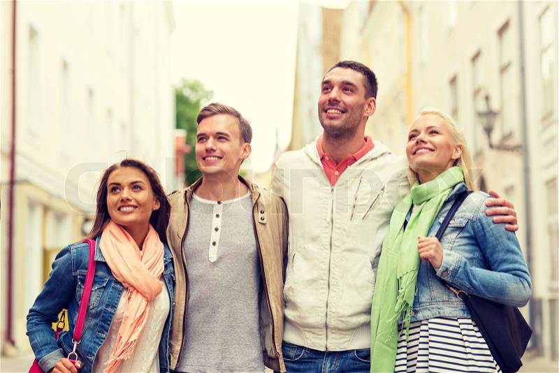 Friendship, travel and vacation concept - group of smiling friends walking in the city, stock photo