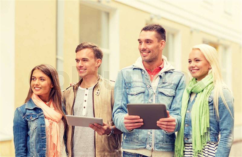 Travel, vacation, technology and friendship concept - group of smiling friends with tablet pc computers in the city, stock photo