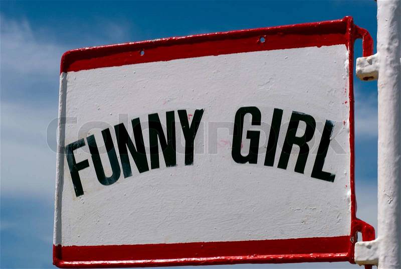 Metal sign on harbor with black text saying FUNNY GIRL, stock photo