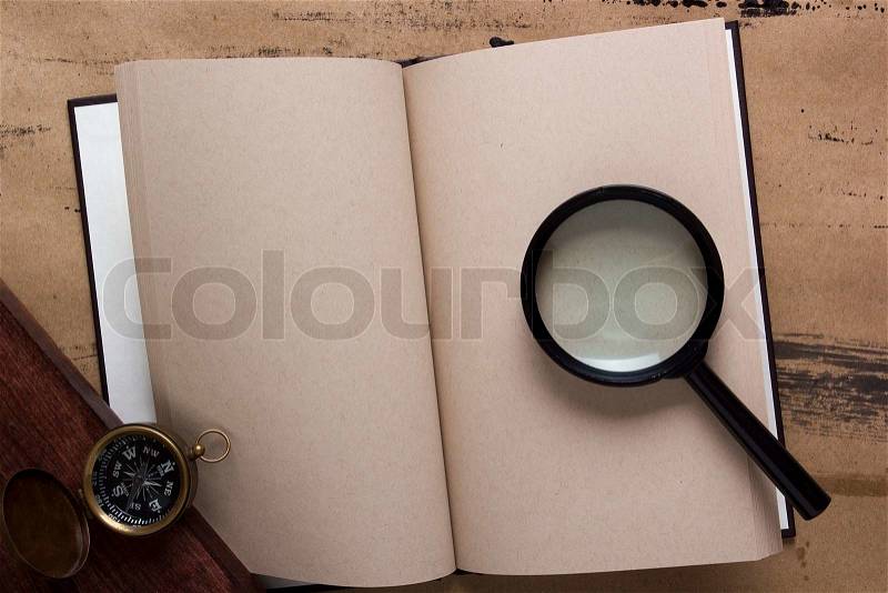 Old book with blank pages, compass and magnifying glass, stock photo