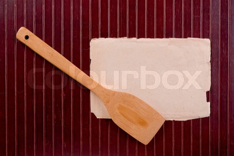Wooden kitchen spatula to mix the ingredients, the ancient parchment for information, stock photo