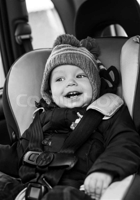 Happy little boy sitting in the car seat in the winter ( black and white ), stock photo