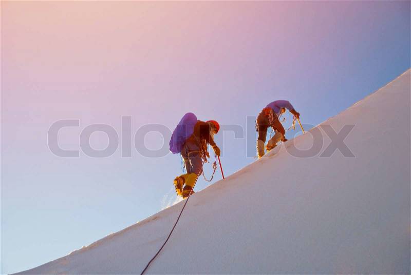 Alpine climbers balances on the ice snowfield, stock photo