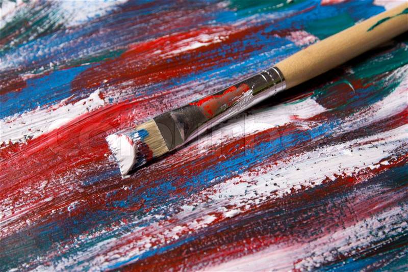 Old brush on acrylic paint background with blue and red strokes, stock photo