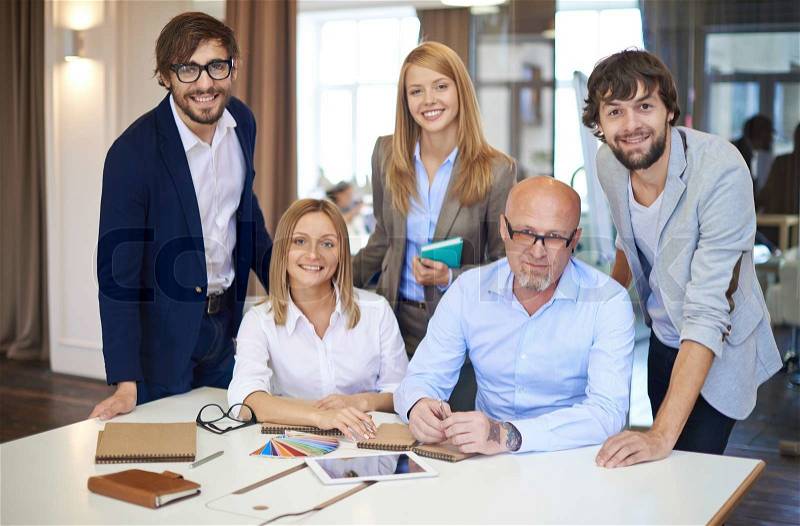Company of smart employees looking at camera in office, stock photo