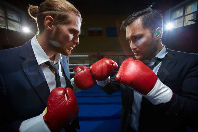 Angry men in suits and boxing gloves attacking one another, stock photo