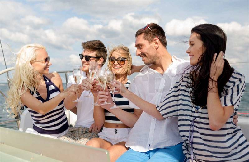 Vacation, travel, sea, friendship and people concept - smiling friends with glasses of champagne on yacht, stock photo