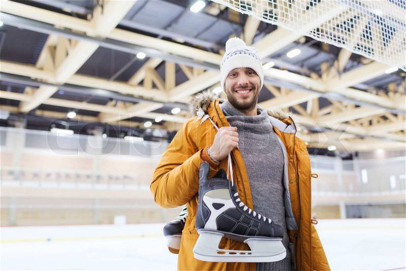 People, sport and leisure concept - happy young man with ice-skates on skating rink, stock photo