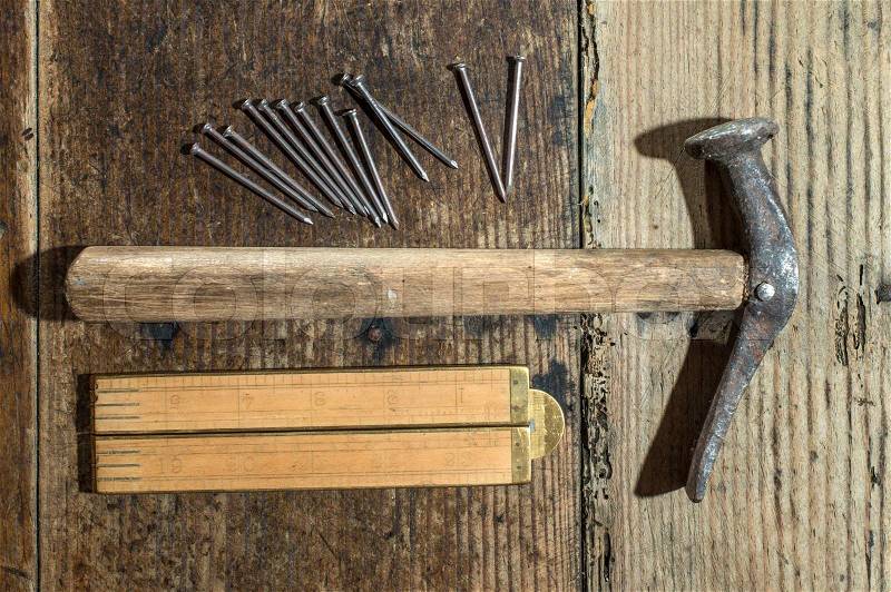 Vintage hammer, nails and wooden centimeter on plank, stock photo