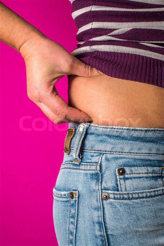 Woman with jeans shows her belly. Overweight, stock photo
