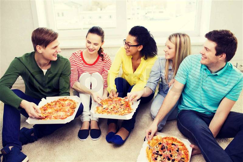 Food, leisure and happiness concept - five smiling teenagers eating pizza at home, stock photo