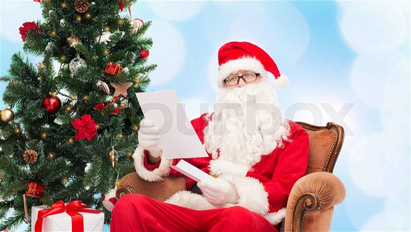 Christmas, holidays and people concept - man in costume of santa claus with letter over blue lights background, stock photo