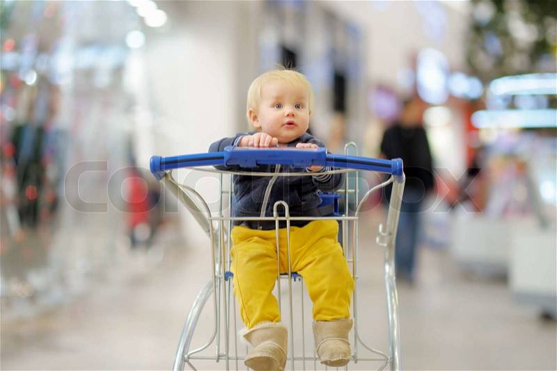 European toddler boy sitting in the shopping cart, stock photo