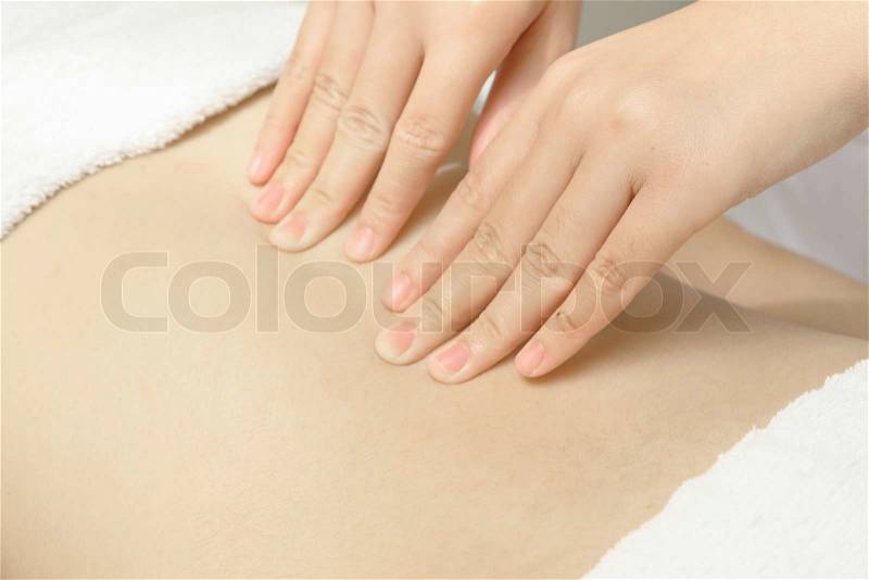 Masseur applying massage techniques to relax back muscles in the spa, stock photo