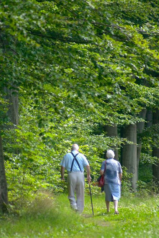 Two old persons / couple in a forest path, stock photo