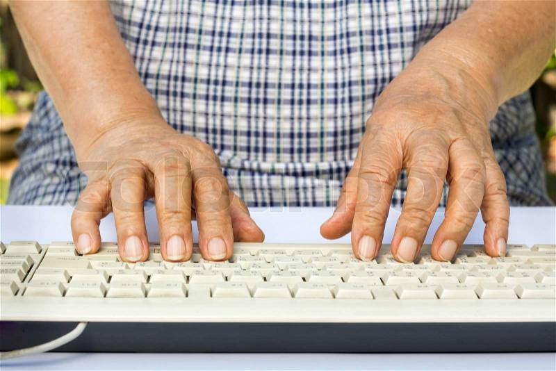 Elderly woman hands on computer keyboard, stock photo