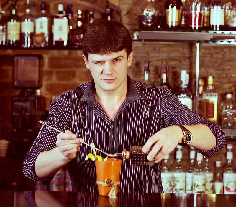 Young man working as a bartender in a nightclub bar, stock photo