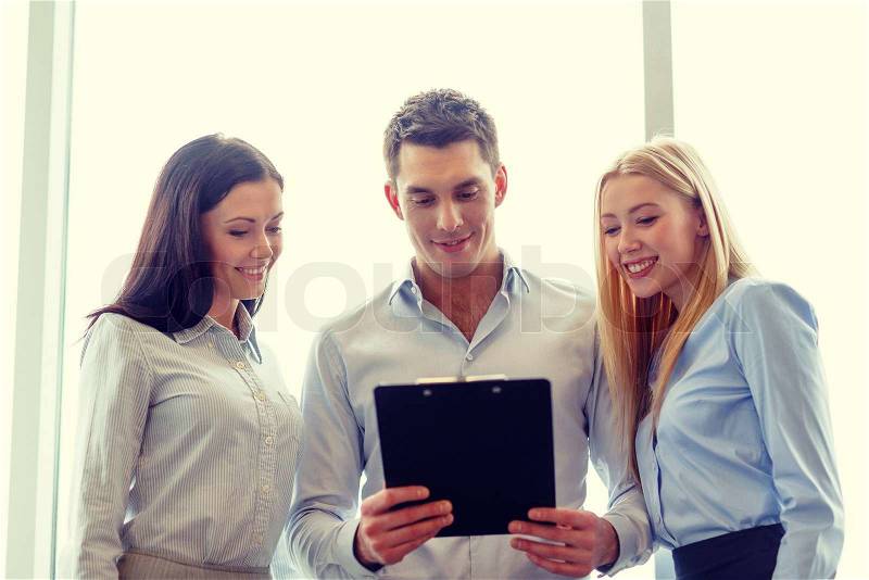 Business and office concept - smiling business team looking at clipboard, stock photo