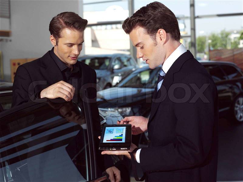 Car salesperson explaining car features to customer, stock photo