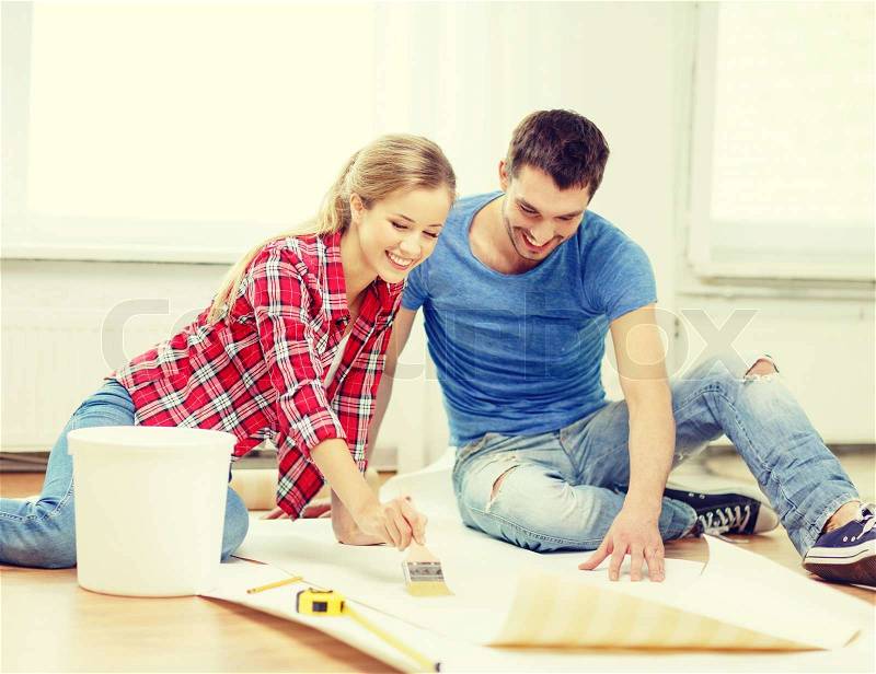Repair, building and home concept - smiling couple smearing wallpaper with glue, stock photo