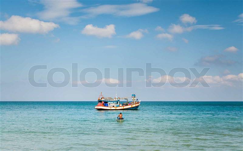 A man paddling a little boat from fishing boat under blue sky, stock photo