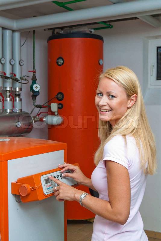 A young woman in the boiler room for heating. Save energy, stock photo