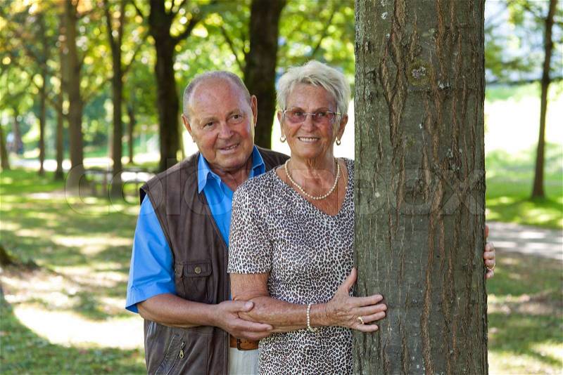 Mature couple is in love senior citizens is a tree in the park, stock photo