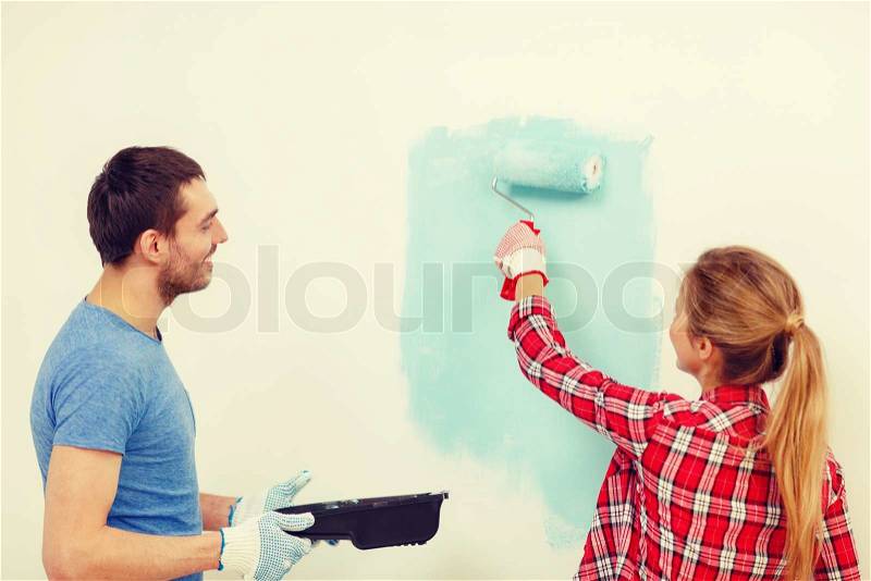 Repair, building and home concept - smiling couple painting wall at home, stock photo