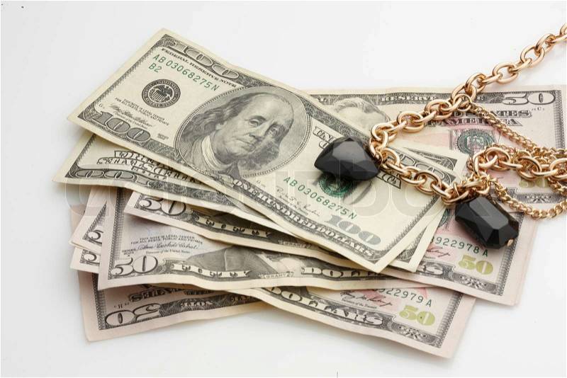 A stack of American dollar bills and gold chain necklace with a black precious stone (stock photo), stock photo