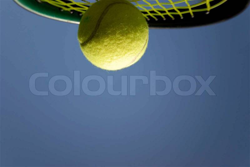 Tennis racket and yellow tennis ball high up and sky blue, stock photo