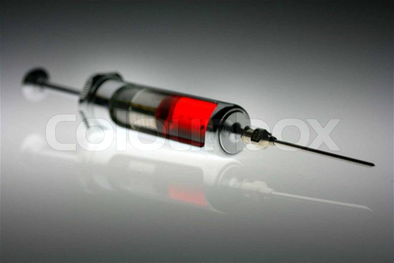 A syringe with red fluid. Symbol of sickness and health, stock photo