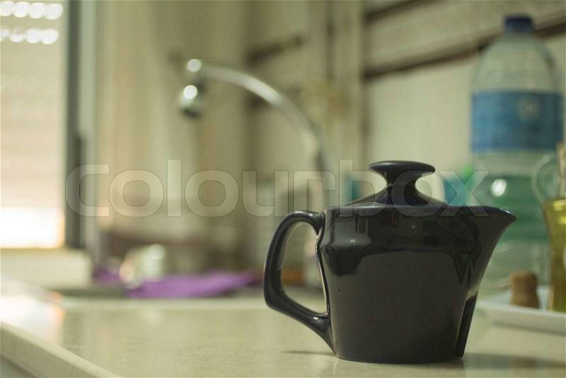 Teapot on domestic home kitchen bench with sink and water bottle in background defocused. , stock photo