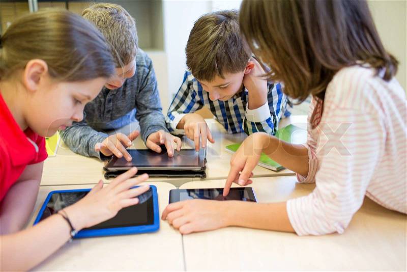 Education, elementary school, learning, technology and people concept - group of school kids with tablet pc computer having fun on break in classroom, stock photo