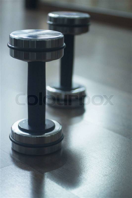 Dumbbell gym metal weights on wooden floor in exercise room in gym health club, stock photo