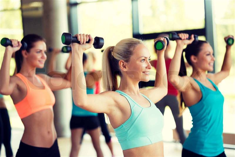 Fitness, sport, training and lifestyle concept - group of women with dumbbells in gym, stock photo