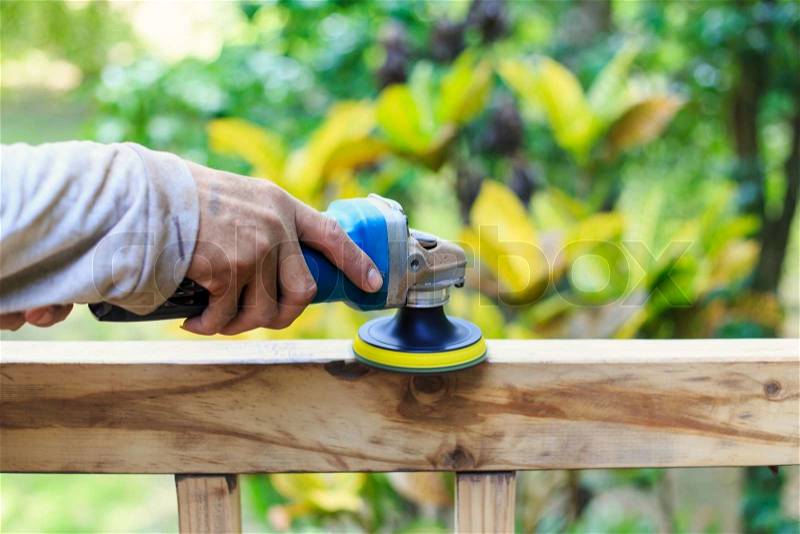 Hand holding angle grinder and work on timber, stock photo