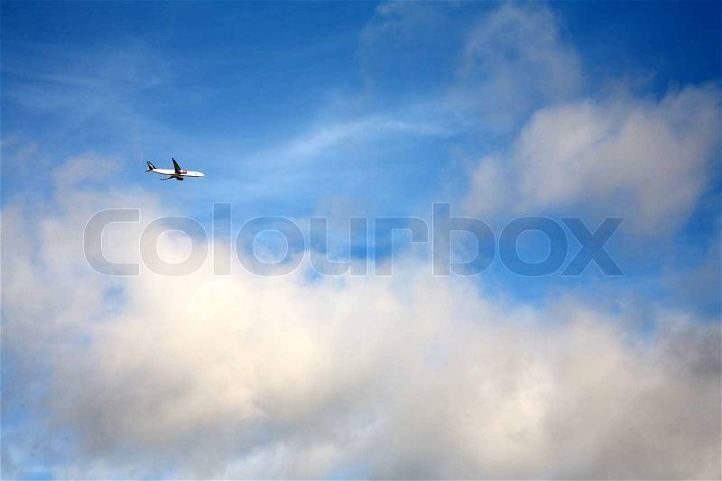 Airplane in a blue sky with nice cloud formation, stock photo