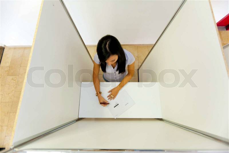 Young woman in a voting booth. Symbol for first-time voters and young voters, stock photo