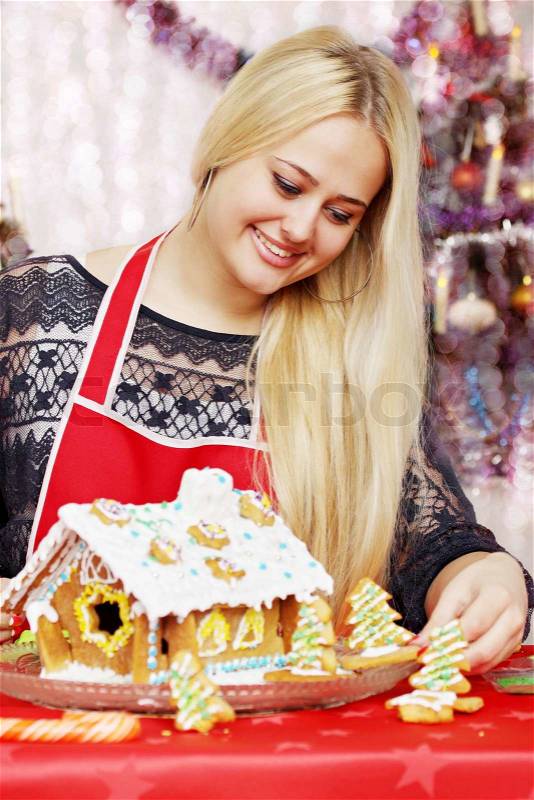 Young beautiful woman decorated gingerbread house, stock photo