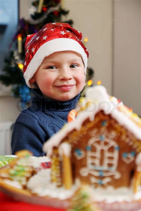 Boy in santa hat near the ginger house, stock photo