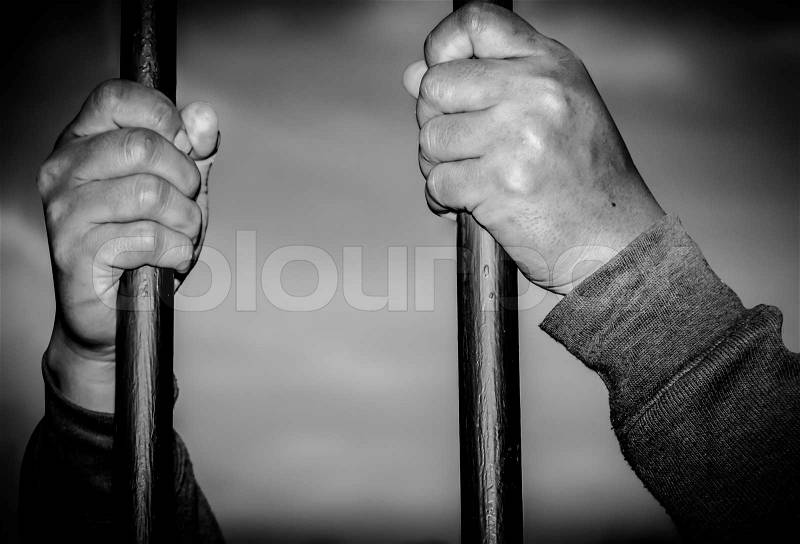 Hands of prisoners catch the nick on gray background, stock photo
