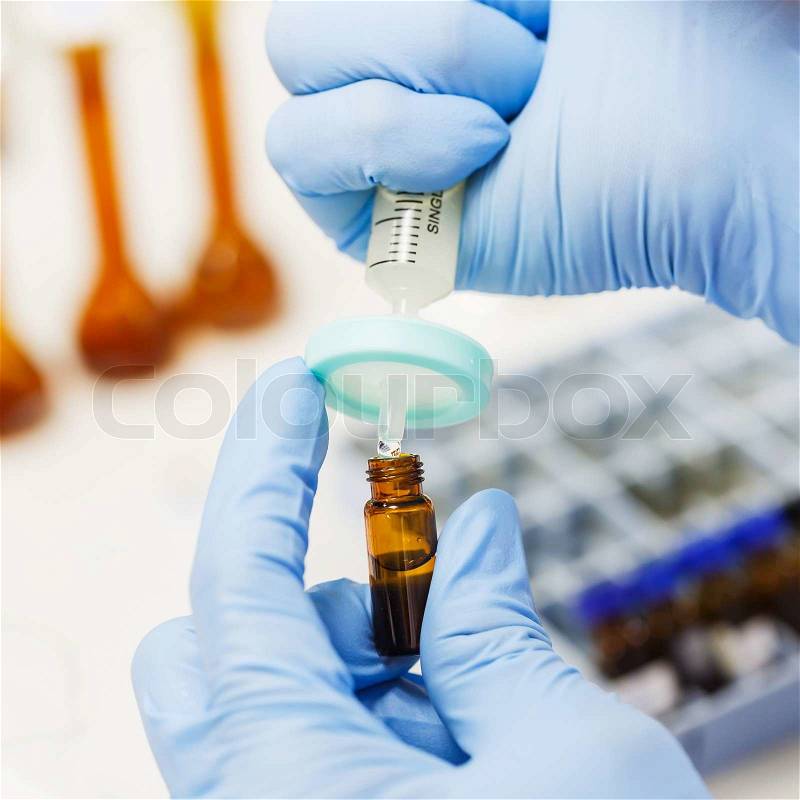 Close up scientist using nylon syringe filter in laboratory, stock photo