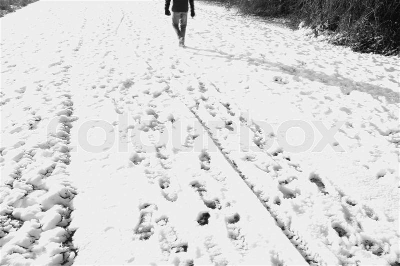 The man walks through the snow in the sun in winter time in black and white, stock photo