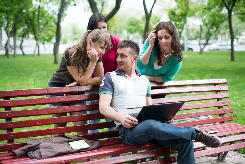 Group of young college students using laptop in the park, stock photo