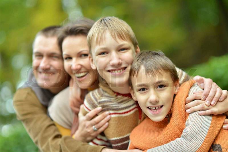 Happy family of four standing together in the park in autumn, stock photo