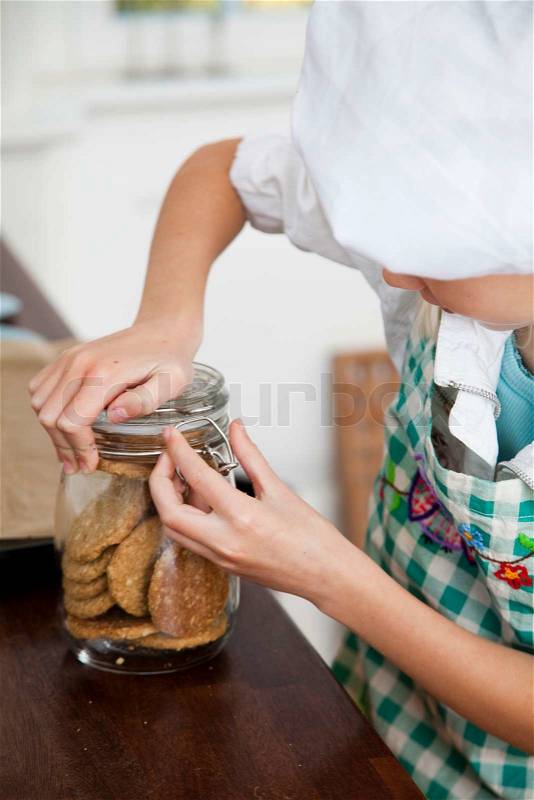 A young girl opening a jar of cookies, stock photo