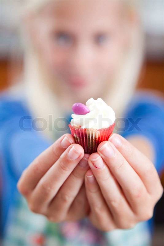 A caucasian girl holding a mini cupcake, stock photo