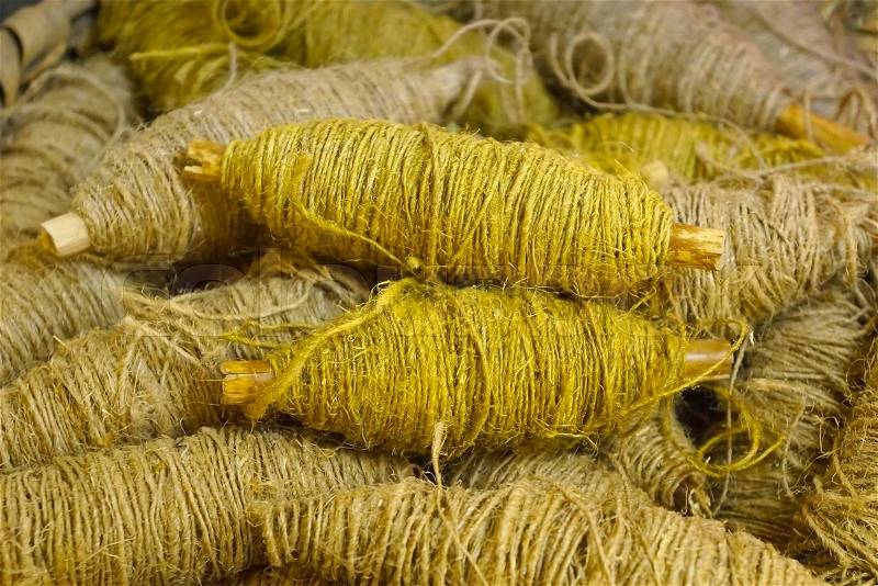 Old bobbin with yellow jute rope background, stock photo