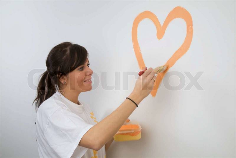 Young woman paints a picture of her first apartment, stock photo